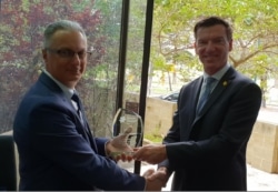 Photo of David Baruffi, Practice Principal and Ashley Reid, CEO of Cancer Council WA, shaking hands and holding commemorative plaque.