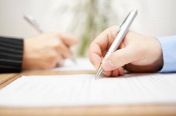Image of hands signing documents with pen
